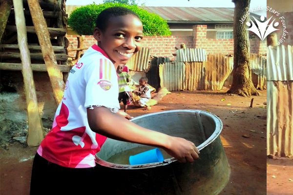 A girl serving a meal from a large cooking pot